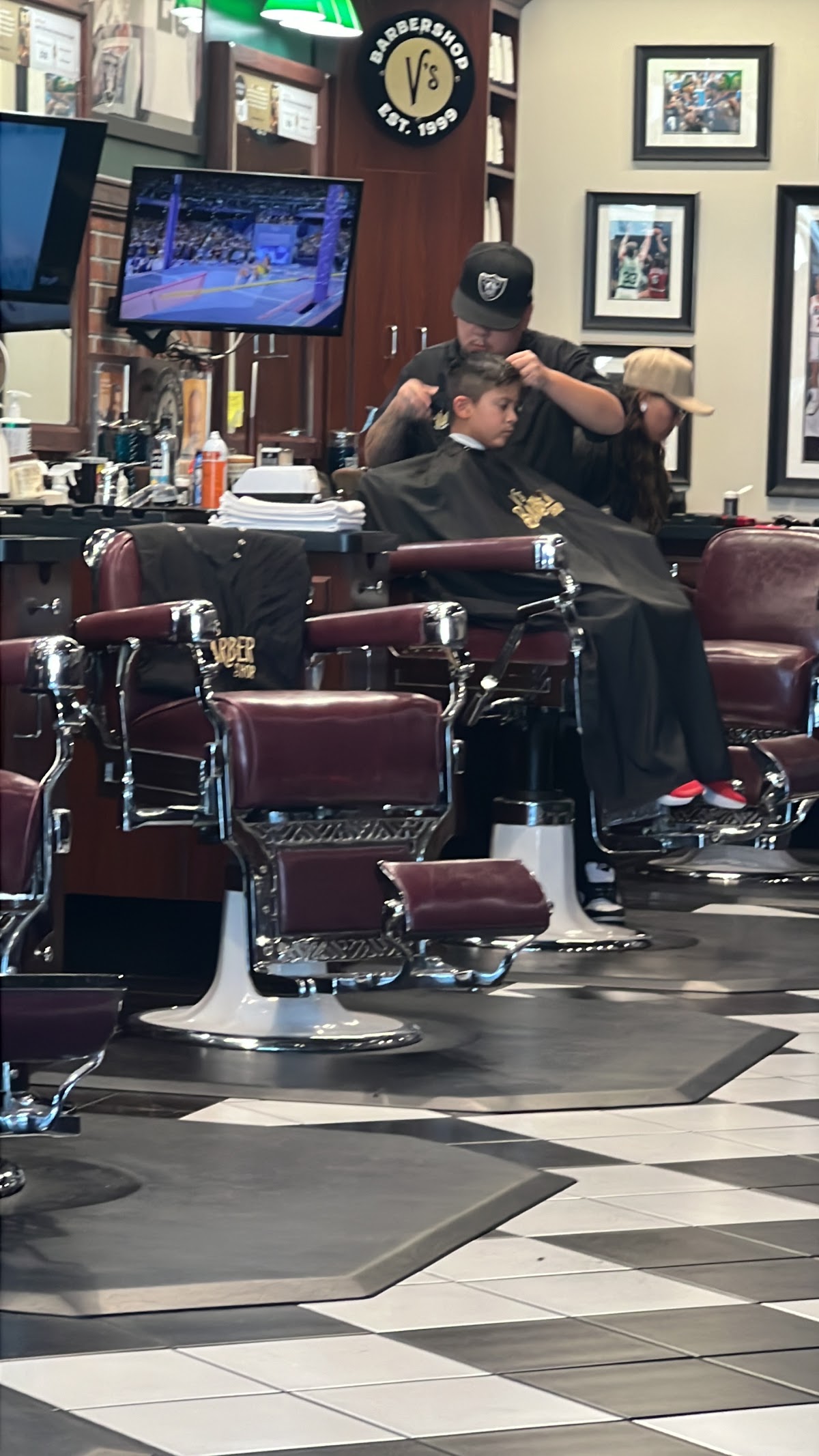 Barber cutting young boy's hair at classic chrome chair