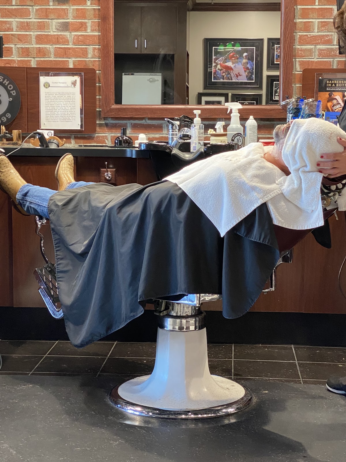 Client reclined in barber chair receiving hot towel treatment